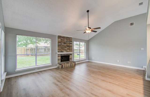 13215 Bunker Hill Dr, Willis, TX 77318 - unfurnished living room featuring ceiling fan, light wood-type flooring, lofted ceiling, a stone fireplace, and baseboards