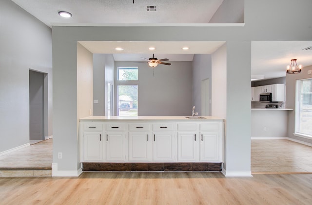 13215 Bunker Hill Dr, Willis, TX 77318 - kitchen featuring a sink, stainless steel microwave, light wood-type flooring, and white cabinets