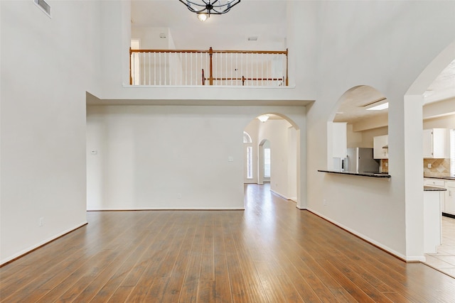 17935 Western Pass Ln, Houston, TX 77095 - unfurnished living room with wood finished floors, a high ceiling, baseboards, and arched walkways