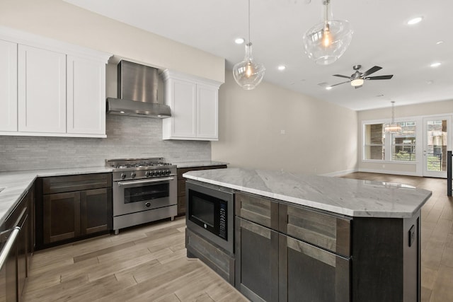 2653 Fountain Key Blvd, Houston, TX 77008 - kitchen with wall chimney exhaust hood, high end stainless steel range, built in microwave, ceiling fan, and backsplash