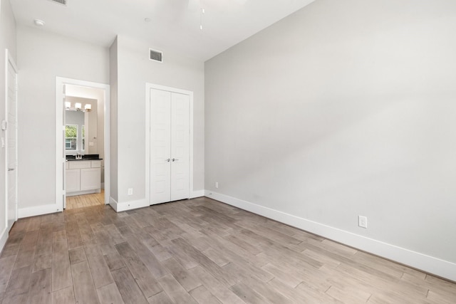 2653 Fountain Key Blvd, Houston, TX 77008 - unfurnished bedroom featuring a chandelier, light wood-style flooring, baseboards, a closet, and connected bathroom