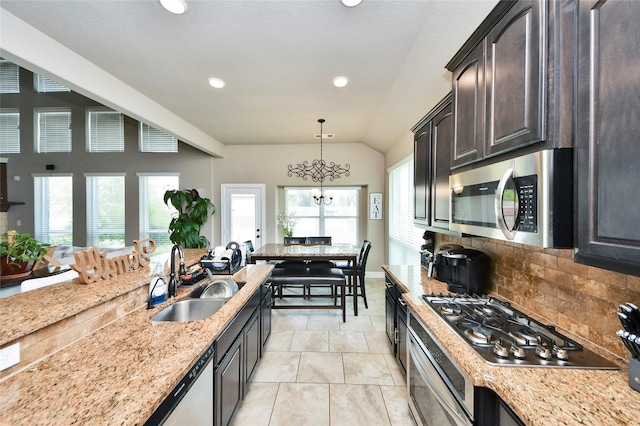 31602 Hummingbird Oak Dr, Hockley, TX 77447 - kitchen featuring appliances with stainless steel finishes, a sink, vaulted ceiling, tasteful backsplash, and light stone counters