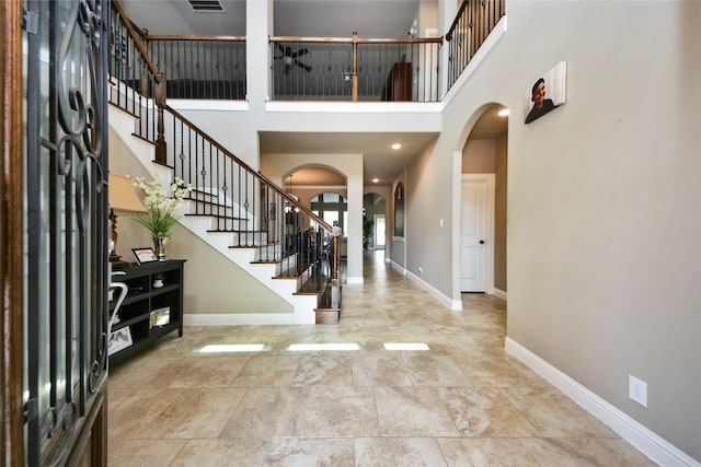 31602 Hummingbird Oak Dr, Hockley, TX 77447 - foyer with arched walkways, a towering ceiling, stairs, and baseboards