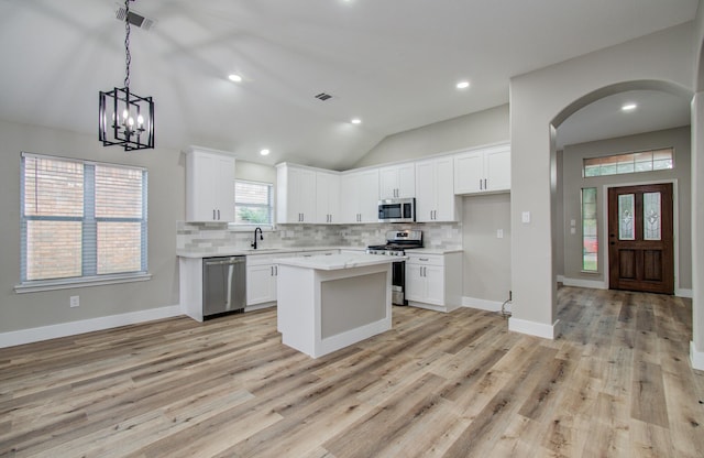 4506 Knights Ct, Baytown, TX 77521 - kitchen featuring appliances with stainless steel finishes, arched walkways, backsplash, a sink, and vaulted ceiling
