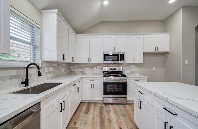 4506 Knights Ct, Baytown, TX 77521 - kitchen with stainless steel appliances, a sink, white cabinetry, light wood-style floors, and lofted ceiling