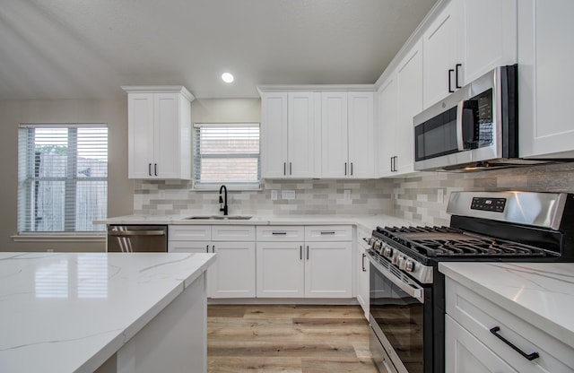 4506 Knights Ct, Baytown, TX 77521 - kitchen featuring appliances with stainless steel finishes, a sink, light wood-type flooring, white cabinets, and light stone counters