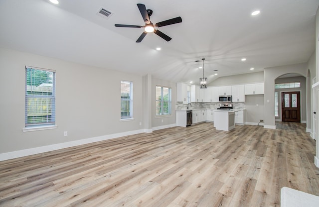 4506 Knights Ct, Baytown, TX 77521 - unfurnished living room featuring lofted ceiling, arched walkways, plenty of natural light, a sink, and ceiling fan