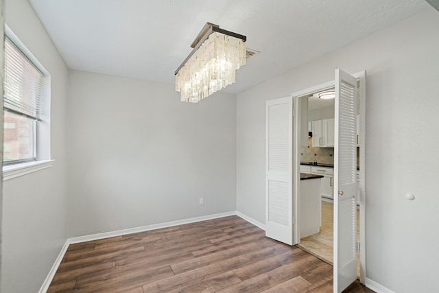 801 Thornwood Dr, Shenandoah, TX 77381 - spare room with wood finished floors, baseboards, and a chandelier