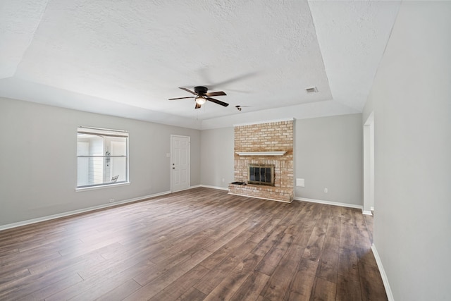 801 Thornwood Dr, Shenandoah, TX 77381 - unfurnished living room featuring a textured ceiling, a ceiling fan, dark wood-style floors, baseboards, and a fireplace