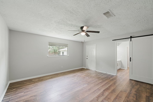 801 Thornwood Dr, Shenandoah, TX 77381 - unfurnished room featuring a barn door, ceiling fan, wood finished floors, a textured ceiling, and baseboards