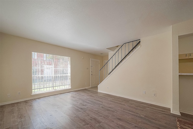 3968 Belle Park Dr, Houston, TX 77072 - unfurnished living room with wood finished floors, stairway, baseboards, and a textured ceiling