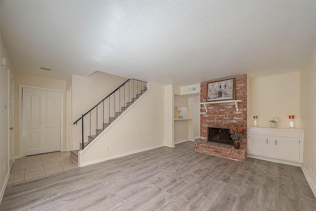 3968 Belle Park Dr, Houston, TX 77072 - unfurnished living room featuring wood finished floors, stairs, a brick fireplace, baseboards, and a textured ceiling