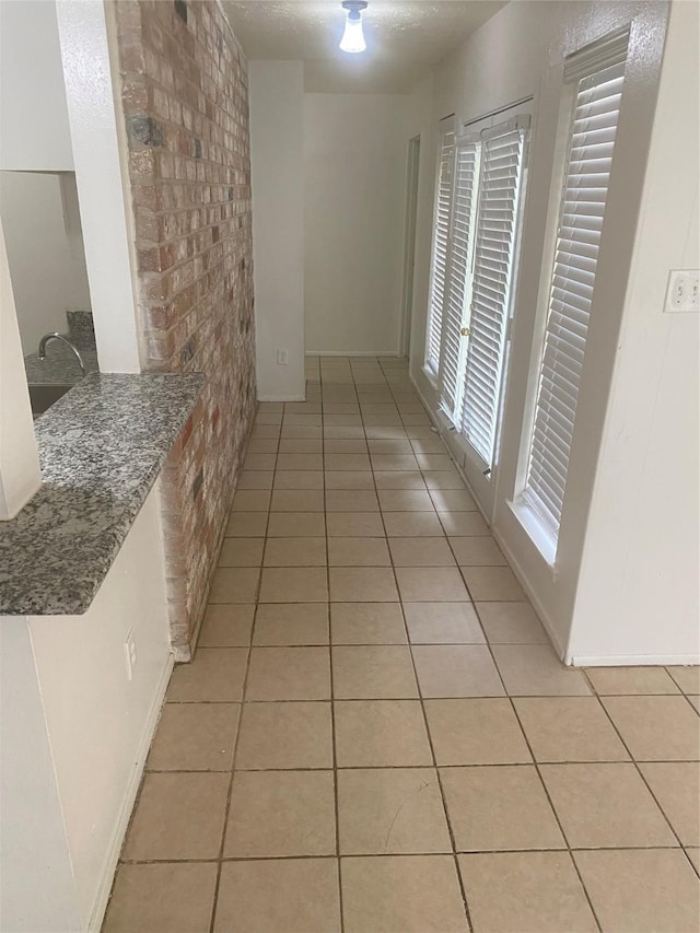 22307 Fincastle Dr, Katy, TX 77450 - hall with light tile patterned floors, brick wall, a sink, and baseboards