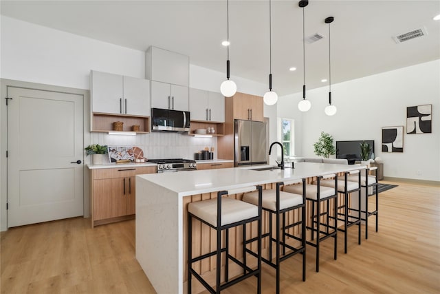2949 Delafield St, Houston, TX 77023 - kitchen featuring appliances with stainless steel finishes, open shelves, a sink, decorative backsplash, and light wood-style floors