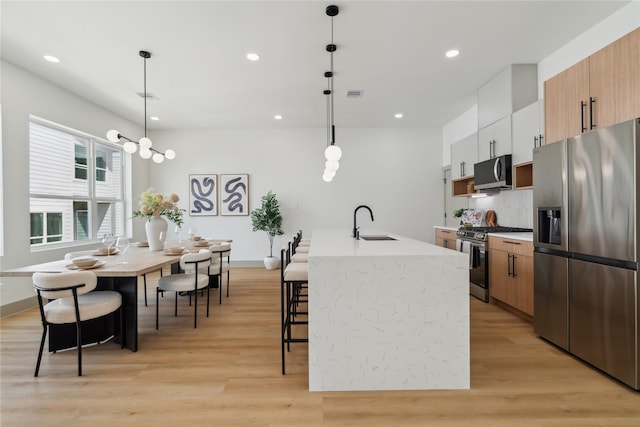 2949 Delafield St, Houston, TX 77023 - kitchen with appliances with stainless steel finishes, a sink, light wood-type flooring, an island with sink, and recessed lighting