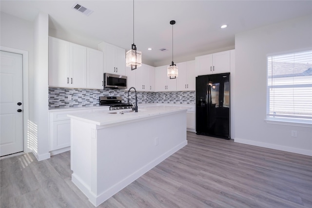 318 New Hampshire St, Houston, TX 77029 - kitchen with appliances with stainless steel finishes, a sink, backsplash, light wood finished floors, and white cabinetry
