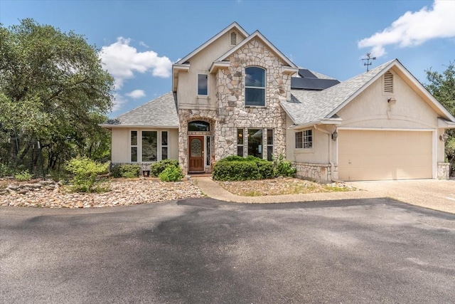 1328 Lakepark Dr, Lakehills, TX 78063 - view of front facade featuring stone siding, asphalt driveway, a shingled roof, a garage, and solar panels