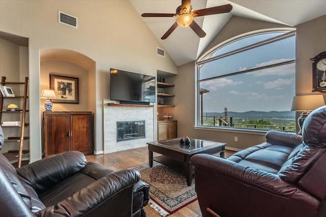 1328 Lakepark Dr, Lakehills, TX 78063 - living area featuring wood finished floors, a ceiling fan, a glass covered fireplace, high vaulted ceiling, and baseboards