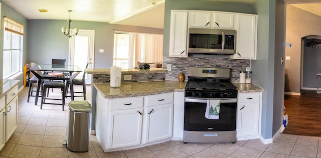 3906 Cyril Dr, Humble, TX 77396 - kitchen featuring appliances with stainless steel finishes, a peninsula, baseboards, and tasteful backsplash