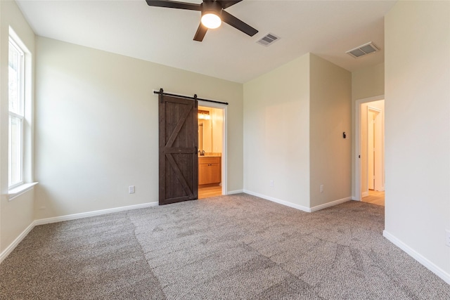 217 E Southland Ave, Alvin, TX 77511 - unfurnished bedroom with a barn door, carpet flooring, baseboards, and a ceiling fan