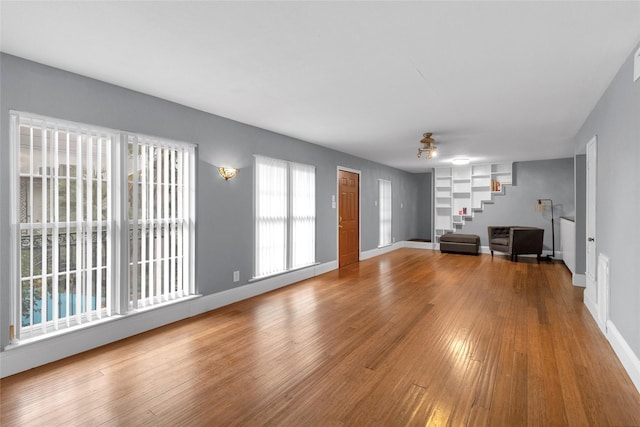 1909 Brun St Unit 17, Houston, TX 77019 - unfurnished living room featuring a ceiling fan, wood finished floors, baseboards, and stairs