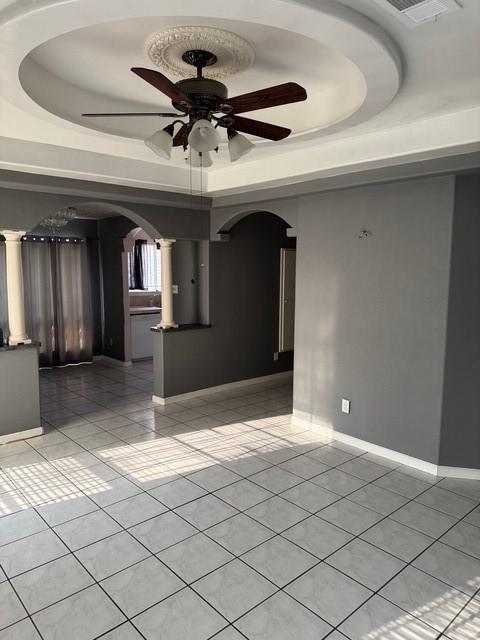 13023 High Star Dr, Houston, TX 77072 - spare room featuring arched walkways, light tile patterned floors, a raised ceiling, a ceiling fan, and decorative columns