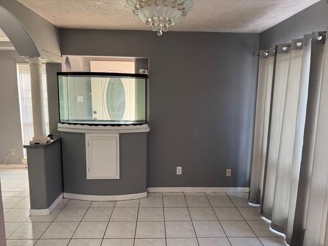 13023 High Star Dr, Houston, TX 77072 - unfurnished room with ornate columns, arched walkways, a textured ceiling, light tile patterned flooring, and baseboards