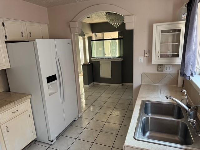 13023 High Star Dr, Houston, TX 77072 - kitchen with a sink, white fridge with ice dispenser, white cabinets, light tile patterned floors, and arched walkways