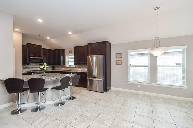 19527 Sundance Edge Ct, Richmond, TX 77407 - kitchen featuring appliances with stainless steel finishes, lofted ceiling, tasteful backsplash, healthy amount of natural light, and light stone countertops