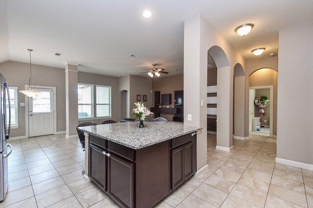 19527 Sundance Edge Ct, Richmond, TX 77407 - kitchen with a ceiling fan, dark brown cabinetry, light stone counters, pendant lighting, and baseboards