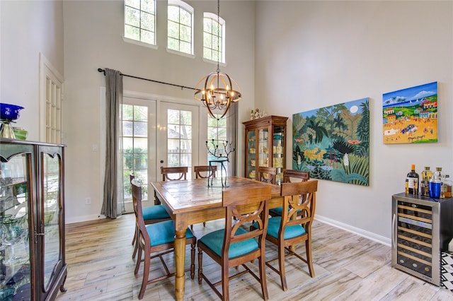 62 W Mirror Ridge Cir, The Woodlands, TX 77382 - dining space featuring a high ceiling, wine cooler, light wood-style flooring, baseboards, and a chandelier
