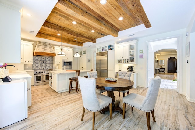 62 W Mirror Ridge Cir, The Woodlands, TX 77382 - dining area featuring arched walkways, recessed lighting, a tray ceiling, wooden ceiling, and light wood-type flooring