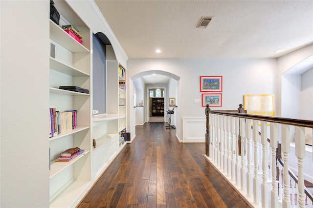 62 W Mirror Ridge Cir, The Woodlands, TX 77382 - corridor with arched walkways, built in features, dark wood-style flooring, a textured ceiling, and recessed lighting