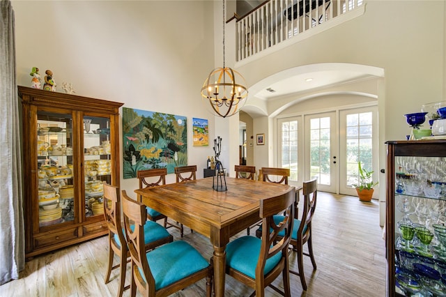 62 W Mirror Ridge Cir, The Woodlands, TX 77382 - dining room featuring arched walkways, french doors, light wood-style flooring, a chandelier, and a high ceiling