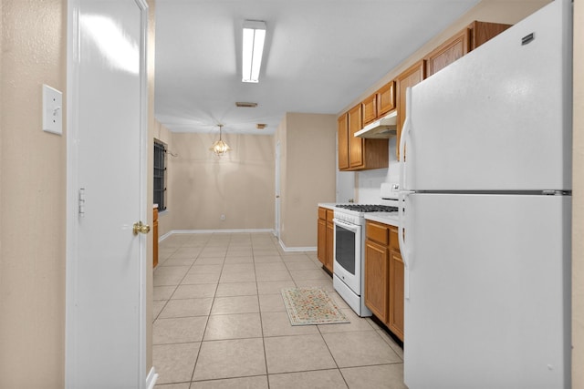 11539 Byronstone Dr, Houston, TX 77066 - kitchen with white appliances, under cabinet range hood, light tile patterned floors, brown cabinetry, and light countertops