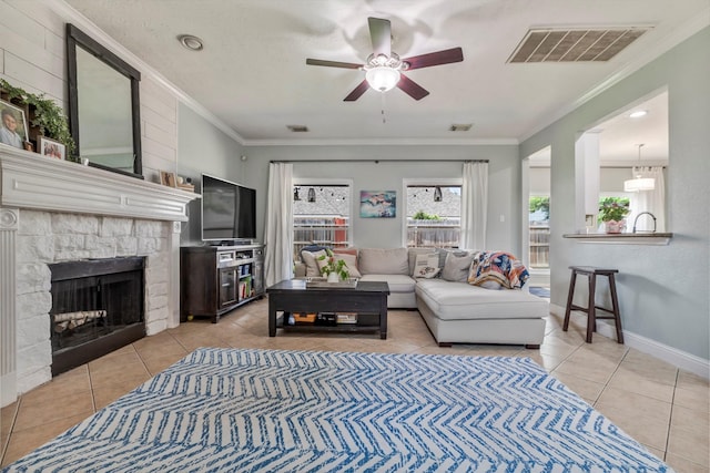 10010 Silverwood Way, Houston, TX 77070 - living room featuring ceiling fan, light tile patterned flooring, a stone fireplace, crown molding, and baseboards