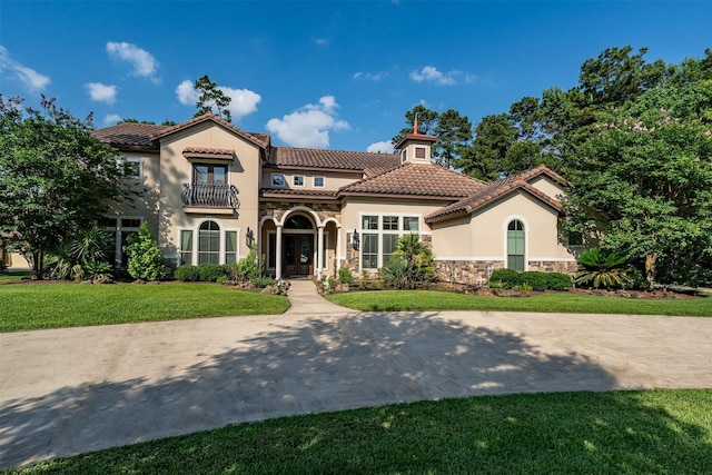 27309 S Lazy Meadow Way, Spring, TX 77386 - mediterranean / spanish-style home with stone siding, stucco siding, a balcony, a tile roof, and a front lawn