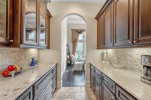 27309 S Lazy Meadow Way, Spring, TX 77386 - kitchen with arched walkways, baseboards, light stone countertops, decorative backsplash, and glass insert cabinets