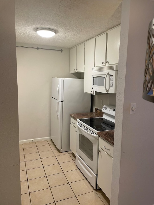 7950 N Stadium Dr Unit 132, Houston, TX 77030 - kitchen with white appliances, a textured ceiling, dark countertops, white cabinets, and light tile patterned floors