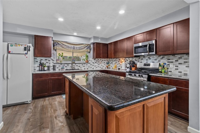 20074 Crazy Horse Circle Dr, Katy, TX 77449 - kitchen with appliances with stainless steel finishes, wood finished floors, a center island, decorative backsplash, and a sink