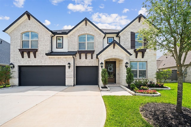 20511 Grazing Foal Ln, Tomball, TX 77377 - french country home featuring an attached garage, concrete driveway, a front lawn, stone siding, and brick siding
