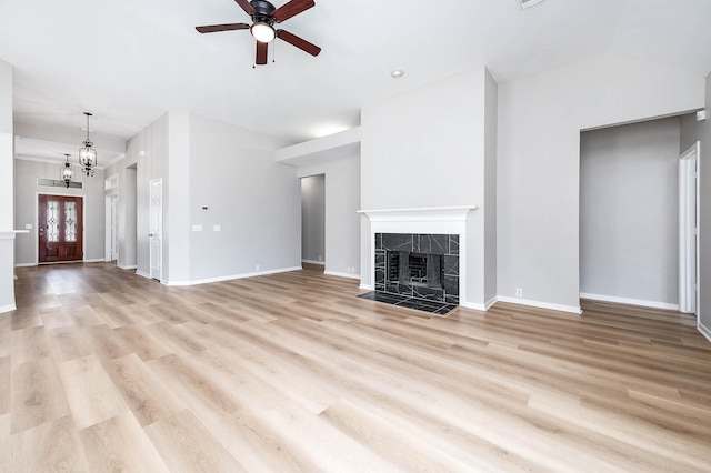 2604 Sunday House Ct, Pearland, TX 77584 - unfurnished living room featuring ceiling fan, a tile fireplace, light wood-type flooring, baseboards, and a chandelier