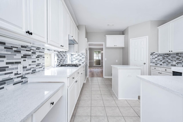 2604 Sunday House Ct, Pearland, TX 77584 - kitchen featuring backsplash, white cabinetry, light tile patterned floors, under cabinet range hood, and stainless steel gas cooktop