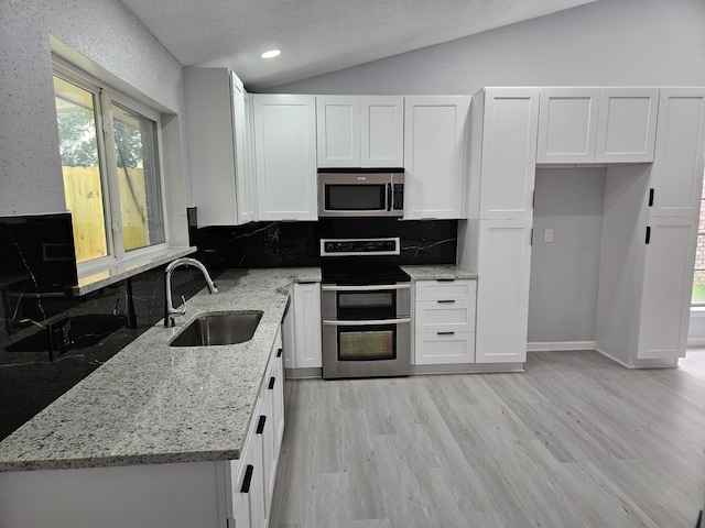 21631 Park Villa Dr, Katy, TX 77450 - kitchen featuring appliances with stainless steel finishes, a sink, lofted ceiling, white cabinetry, and backsplash