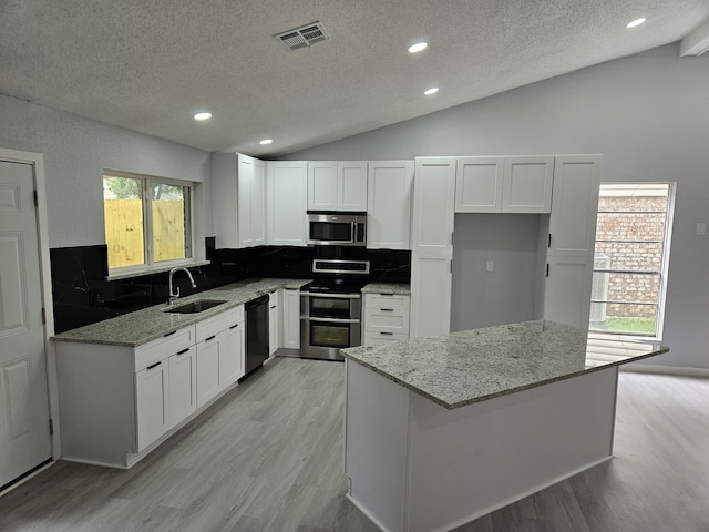 21631 Park Villa Dr, Katy, TX 77450 - kitchen featuring appliances with stainless steel finishes, a sink, vaulted ceiling, a textured ceiling, and light wood-type flooring