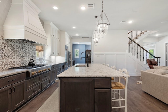 415 Faust Ln, Houston, TX 77024 - kitchen featuring stainless steel gas stovetop, a sink, custom range hood, dark brown cabinets, and dark wood finished floors