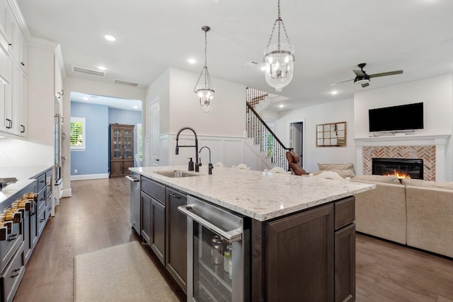 415 Faust Ln, Houston, TX 77024 - kitchen featuring a sink, beverage cooler, dark brown cabinetry, a fireplace, and wood finished floors