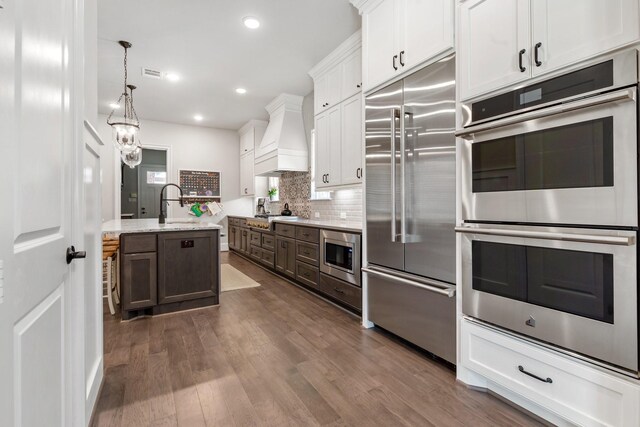 415 Faust Ln, Houston, TX 77024 - kitchen with built in appliances, premium range hood, white cabinets, decorative backsplash, and dark wood-style floors