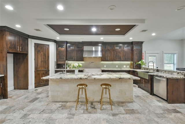 7737 Brookside Rd, Pearland, TX 77581 - kitchen featuring stainless steel dishwasher, a sink, wall chimney exhaust hood, a raised ceiling, and a peninsula