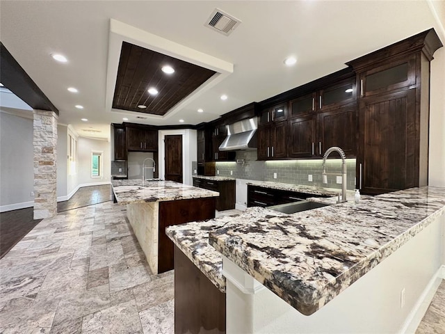 7737 Brookside Rd, Pearland, TX 77581 - kitchen with a sink, wall chimney range hood, backsplash, stone tile floors, and baseboards